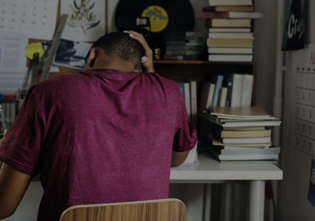 Teenage boy in a bedroom doing work stressed out and frustrated